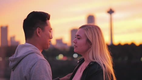 Multiethnic-Young-Couple-Talking-On-The-Bridge-Against-The-Backdrop-Of-A-Big-City-And-A-Beautiful-Su