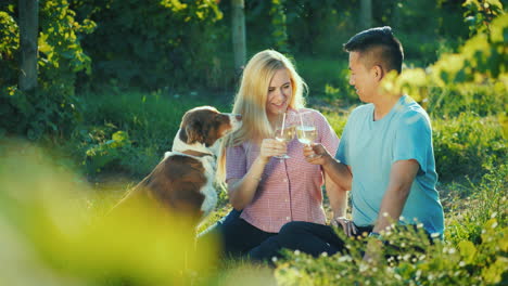 Glückliches-Paar,-Das-Wein-In-Der-Nähe-Des-Weinbergs-Verkostet,-Ihr-Hund-In-Ihrer-Nähe-Glücklich-Zusammen-Gutes-Zeitkonzept