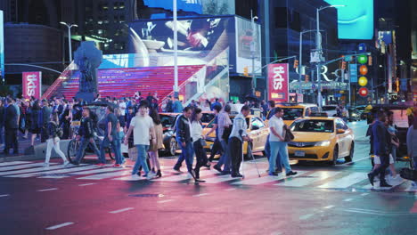 A-Crowd-Of-Pedestrians-Crossing-The-Street-In-Times-Square-Advertising-Lights-Highlight-The-Street