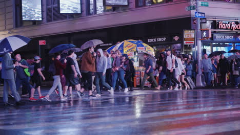 Eine-Menge-Fußgänger-Mit-Regenschirmen-In-Der-Hand,-Die-Es-Eilig-Haben,-Die-Straße-In-Einer-Belebten-Gegend-Zu-überqueren