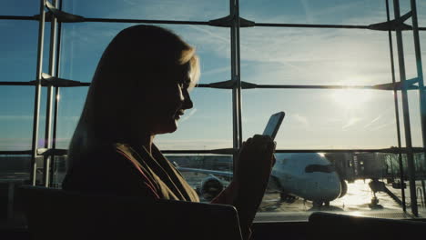 Geschäftsfrau,-Die-Darauf-Wartet,-Ihren-Flug-Am-Flughafenterminal-Mit-Einem-Smartphone-Zu-Besteigen
