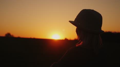 Eine-Frau-Mit-Hut-Freut-Sich-Auf-Die-Sonnenuntergangshoffnung-Und-Das-Strahlende-Zukunftskonzept-4k-Zeitlupenvideo