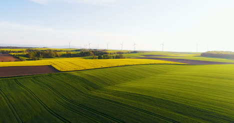 Aerial-View-Of-Summer-Countryside-With-Wind-Turbines-And-Agricultural-Fields