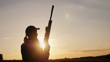 Silhouette-Of-A-Woman-With-A-Rifle-In-The-Rays-Of-A-Sunset-Sports-Shooting-4K-Video