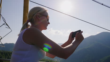 A-Young-Woman-Is-Riding-On-A-Ski-Lift-On-A-Summer-Day-He-Takes-Pictures-Of-Beautiful-Landscapes-Holi