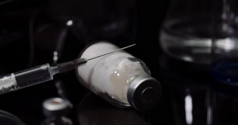 Laborausrüstung:-Spritzen--Und-Medizin-Reagenzgläser-Und--Kolben-Rotieren-Auf-Schwarzem-Hintergrund