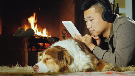 Asian-Man-Uses-A-Tablet-Lies-Near-The-Fireplace-02