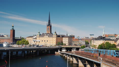 La-Línea-De-La-Ciudad-De-Estocolmo-En-Primer-Plano,-El-Tren-Pasa-El-Transporte-En-La-Capital-De-Suecia