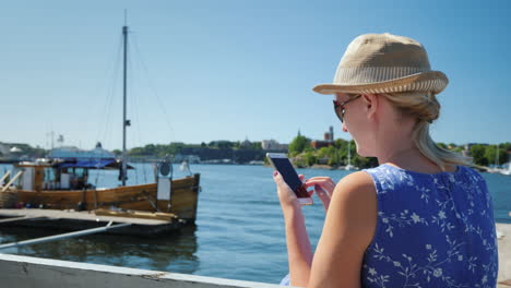 Eine-Ruhende-Frau-Mit-Smartphone-Sitzt-Auf-Der-Böschung-Vor-Der-Kulisse-Des-Meeres-Und-Legt-Fest