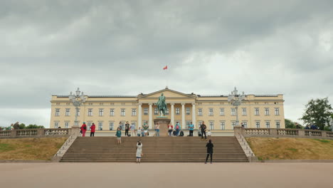 Prächtiges-Gebäude-Des-Königlichen-Palastes-In-Oslo-Touristen-Laufen-In-Der-Nähe
