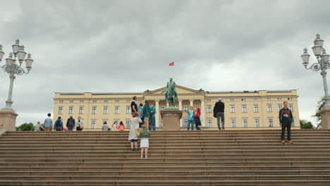 Prächtiges-Gebäude-Des-Königlichen-Palastes-In-Oslo-Touristen-Laufen-In-Der-Nähe