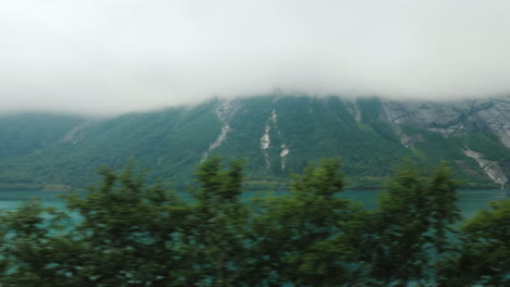 Go-In-The-Fog-Along-The-Forest-View-From-The-Car-Window-Driving-In-Poor-Visibility-High-In-The-Mount
