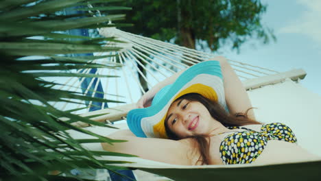 A-Pretty-Brunette-In-A-Wide-Brimmed-Hat-And-In-A-Bikini-Enjoys-Relaxing-In-The-Seaside-Resort-Lies-O