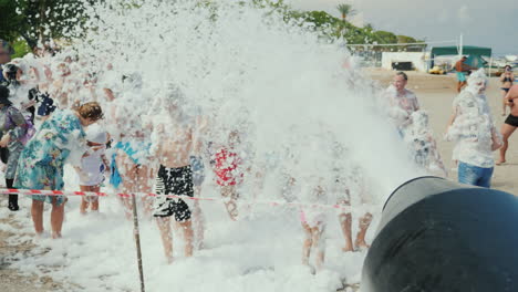 A-Crowd-Of-Vacationers-Have-Fun-On-The-Beach-Under-The-Streams-Of-Foam-Foam-Party-On-The-Beach-Enter
