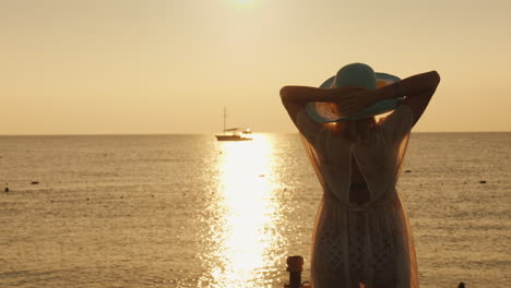 A-Young-Woman-In-A-Light-Dress-And-Hat-Meets-The-Dawn-At-The-Sea-A-Ship-Is-Visible-In-The-Distance-D