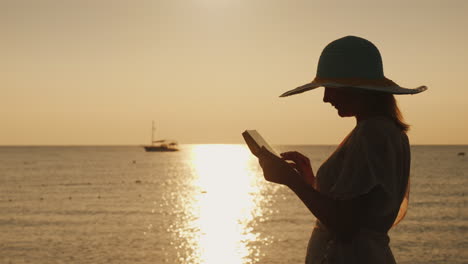 Silhouettes-A-Young-Woman-In-A-Wide-Brimmed-Hat-That-Uses-A-Tablet-Against-The-Backdrop-Of-A-Beautif