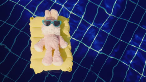 Ein-Cooler-Hase-In-Sonnenbrille-Leuchtet-Auf-Einer-Aufblasbaren-Matratze-Schwebt-Im-Poolurlaub-Mit-Kind