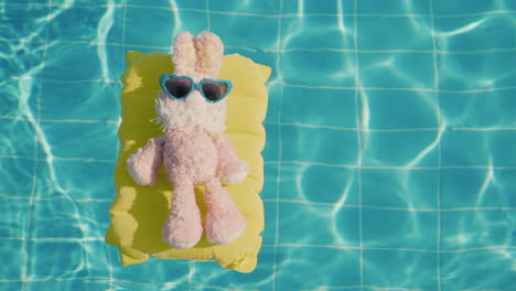 Ein-Cooler-Hase-In-Sonnenbrille-Leuchtet-Auf-Einer-Aufblasbaren-Matratze-Schwebt-Im-Poolurlaub-Mit-Kind