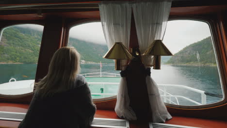 A-Woman-Looks-Out-Of-The-Porthole-At-The-Beautiful-Scenery-Of-Norway-Floats-On-A-Ship-On-The-Norwegi