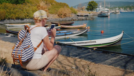 Eine-Frau-Mit-Rucksack-Sitzt-Am-Wasser-Der-Stadt-Oslo-In-Norwegen-In-Der-Nähe-Der-Fischerboote