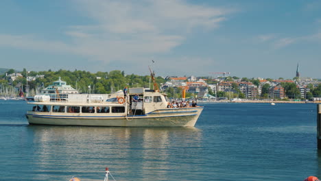 Ein-Kleines-Kreuzfahrtschiff-Mit-Touristen,-Die-Auf-Dem-Hintergrund-Der-Stadtlinie-Von-Oslo-.-Schwimmen