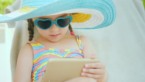 A-Cool-Girl-In-Sunglasses-In-The-Shape-Of-A-Heart-Uses-A-Smartphone-On-Vacation-4k-Video