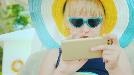 Ein-Cooles-Mädchen-Mit-Sonnenbrille-In-Herzform-Benutzt-Ein-Smartphone-Im-Urlaub-4k-Video-4