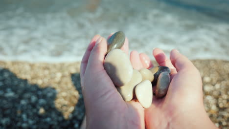 Female-Hands-Hold-A-Handful-Of-Wet-Pebbles-Rest-On-The-Sea-Meditación-Concept-4k-Video