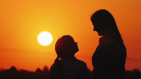 Mama-Und-Tochter-Schauen-Gemeinsam-Den-Wunderschönen-Sonnenuntergang-über-Der-Stadt-Und-Den-Orangefarbenen-Himmel-An