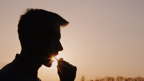 Profile-Of-A-Teenager-Eating-Snacks-Silhouette-Against-The-Setting-Sun