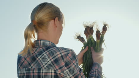 Back-View-Of-A-Female-Farmer-With-A-Green-Onion-In-Her-Hands-Organic-Farming-Concept