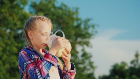 Ein-Mädchen-Trinkt-Milch-Aus-Einem-Glaskrug-In-Ihrem-Garten-Gesundes-Bio-Produktkonzept