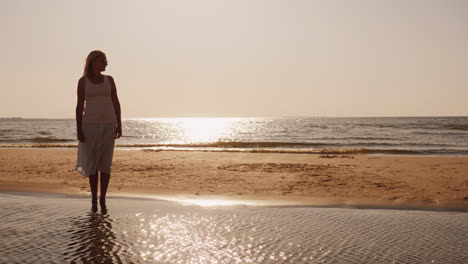 Einsame-Silhouette-Eines-Jungen-Mannes,-Der-Auf-Dem-Sand-Am-Meer-Sitzt