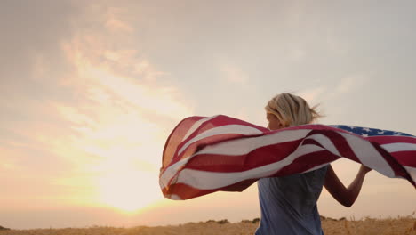 Frau-Mit-USA-Flagge-Läuft-In-Der-Sonne-Auf-Einem-Weizenfeld