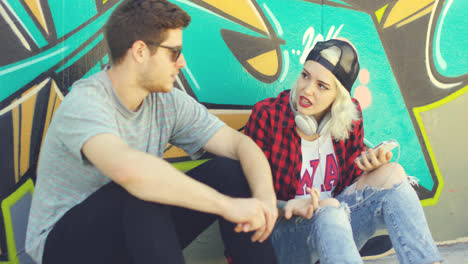 Young-hipster-urban-couple-relaxing-on-a-sidewalk
