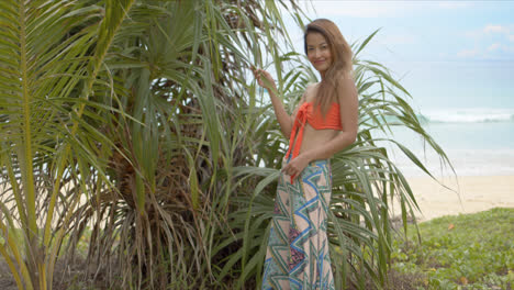 Stylish-lady-touching-tropical-plant-on-beach