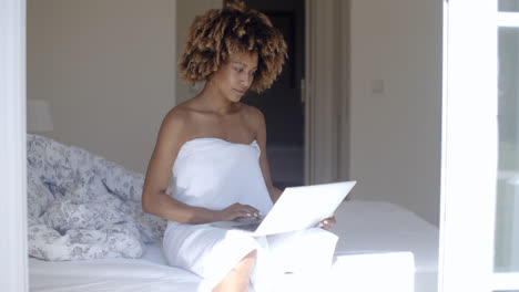 Young-Woman-Using-Laptop-On-Bed