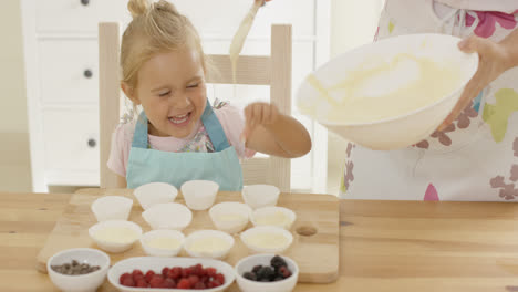 Girl-laughing-as-batter-is-poured-into-muffin-cups