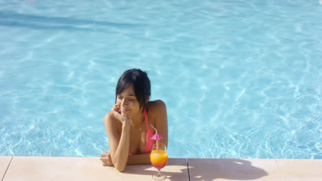Contented-woman-at-pool-edge-with-drink