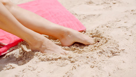 Close-up-Woman-Feet-Resting-on-Beach-Sand
