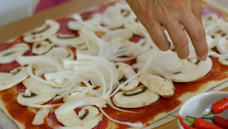 Mujer-Colocando-Cebolla-En-Una-Pizza-Casera
