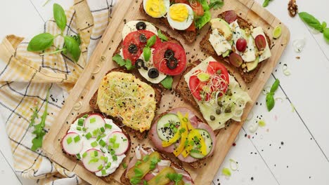 Tasty--homemade-small-sandwiches-with-various-ingredients-served-on-wooden-chopping-board