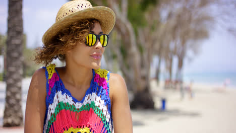 Grinning-woman-in-sunglasses-and-hat-near-ocean