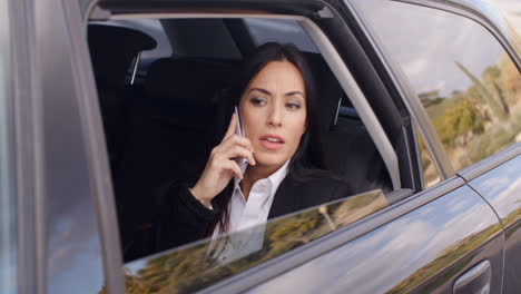 Serious-female-executive-on-phone-in-limousine