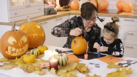 Woman-and-girl-painting-face-on-pumpkin