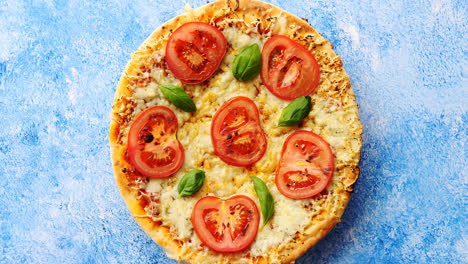 Pizza-with-cheese-and-tomatoes-on-blue-stone-table