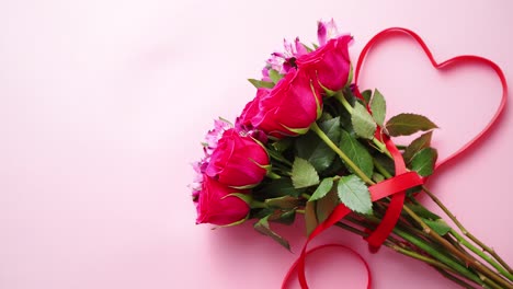 Gemischter-Blumenstrauß-Mit-Rosen-Und-Herzförmiger-Schleife-Auf-Rosa-Hintergrund