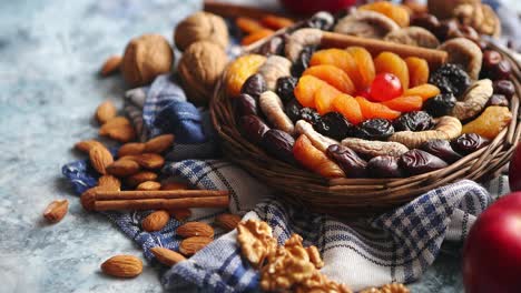 Composition-of-dried-fruits-and-nuts-in-small-wicker-bowl-placed-on-stone-table