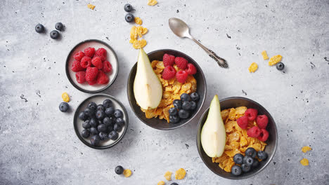 Golden-cornflakes-with-fresh-fruits-of-raspberries--blueberries-and-pear-in-ceramic-bowl
