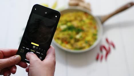 Woman-taking-a-photos-with-mobile-phone-of-delicious-fried-rice-with-chicken-served-in-pan